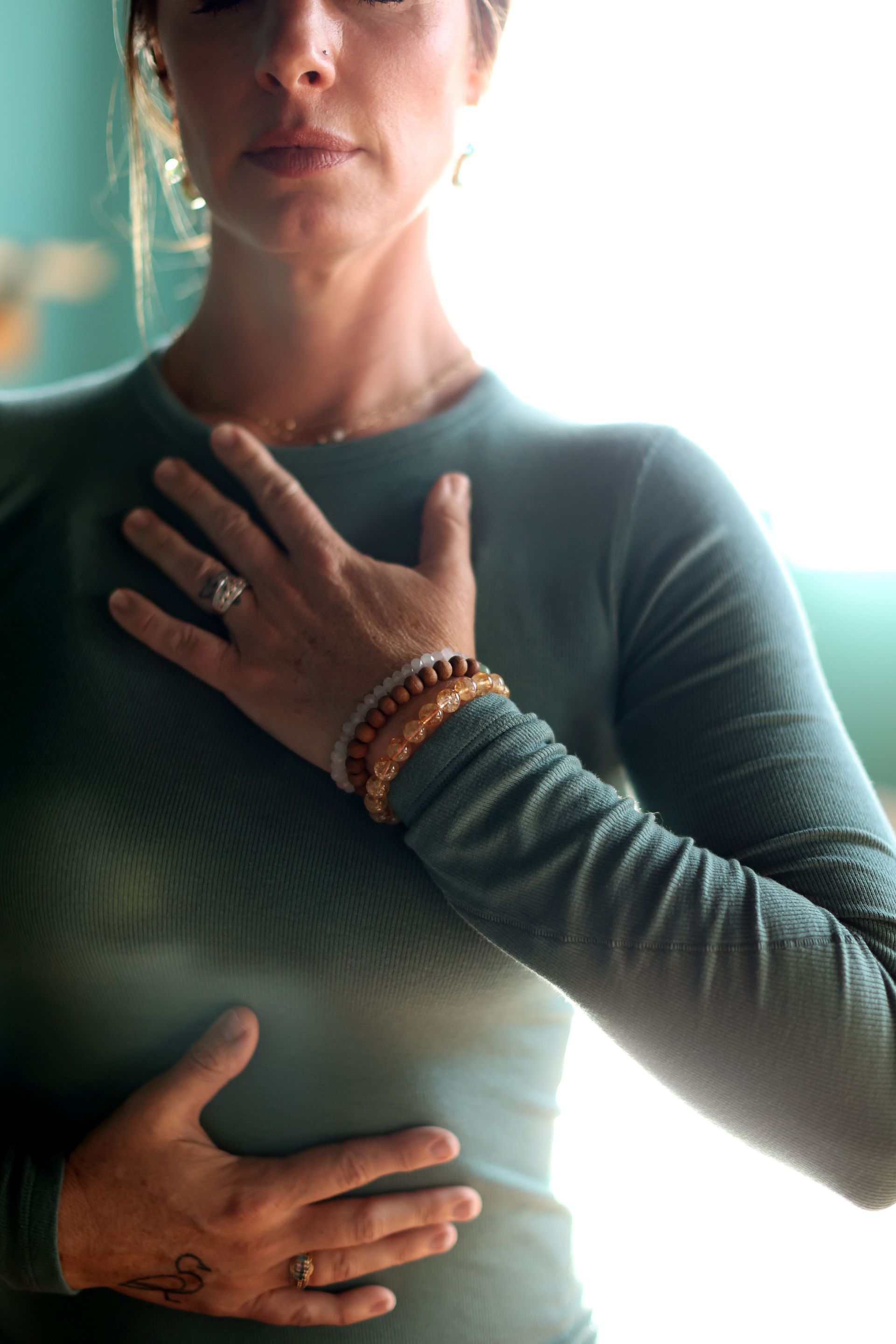 Woman in green top with hands on chest, practicing breathwork.