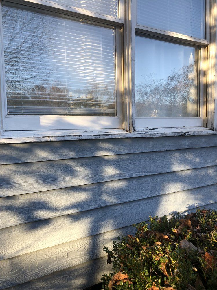 A window with blinds on it is on the side of a house.