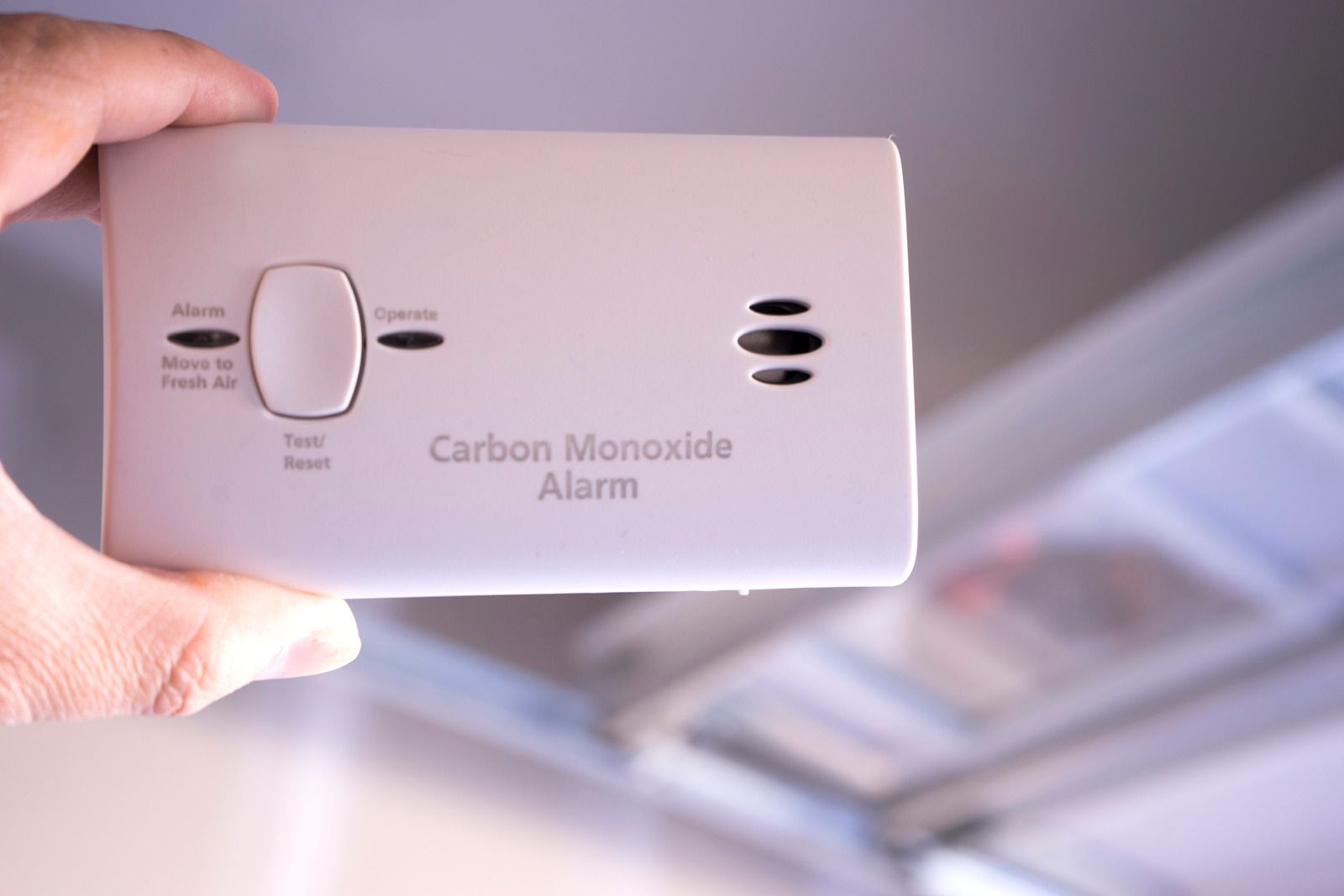 A person is holding a carbon monoxide alarm in their hand.