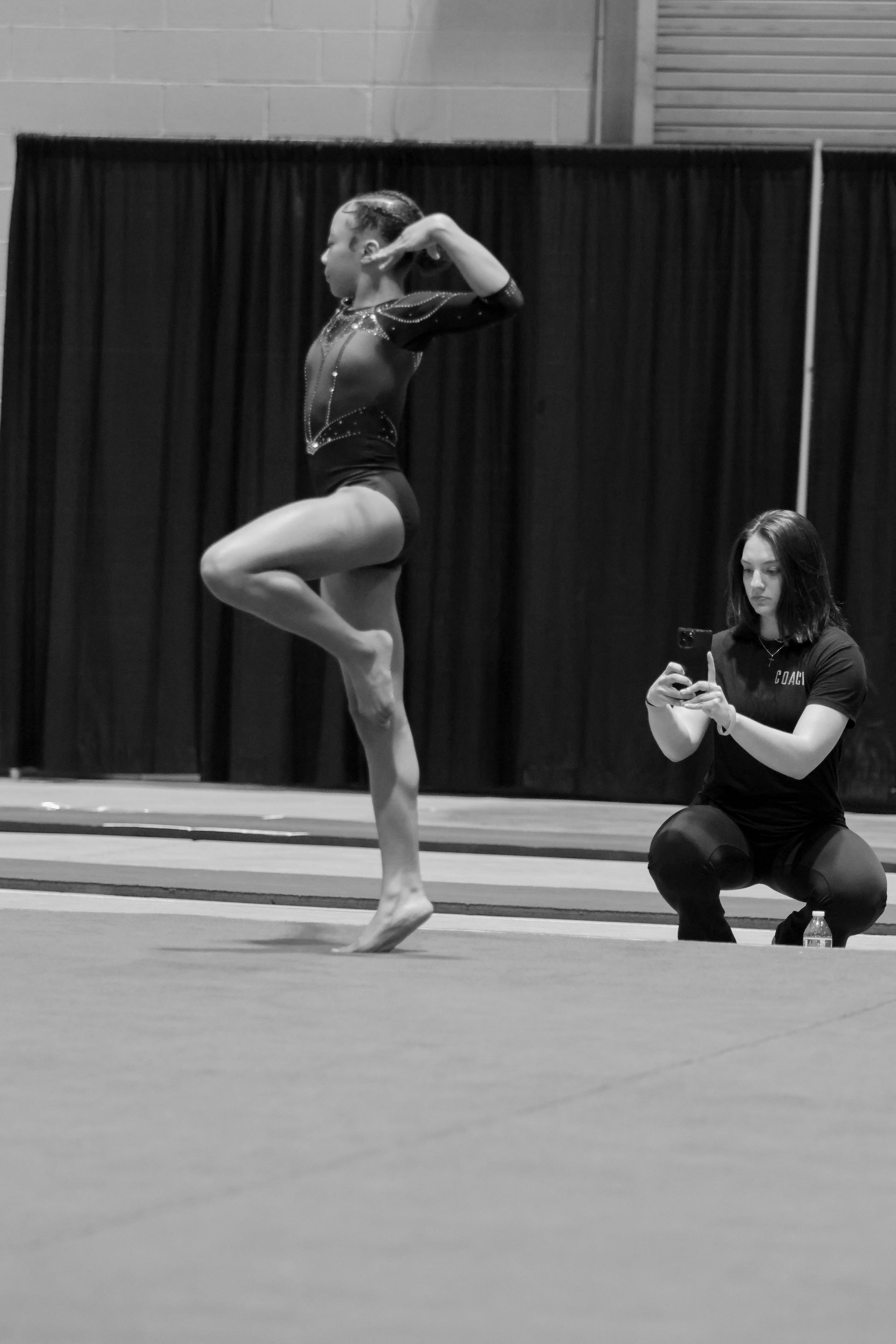 A woman is taking a picture of a gymnast on a mat.