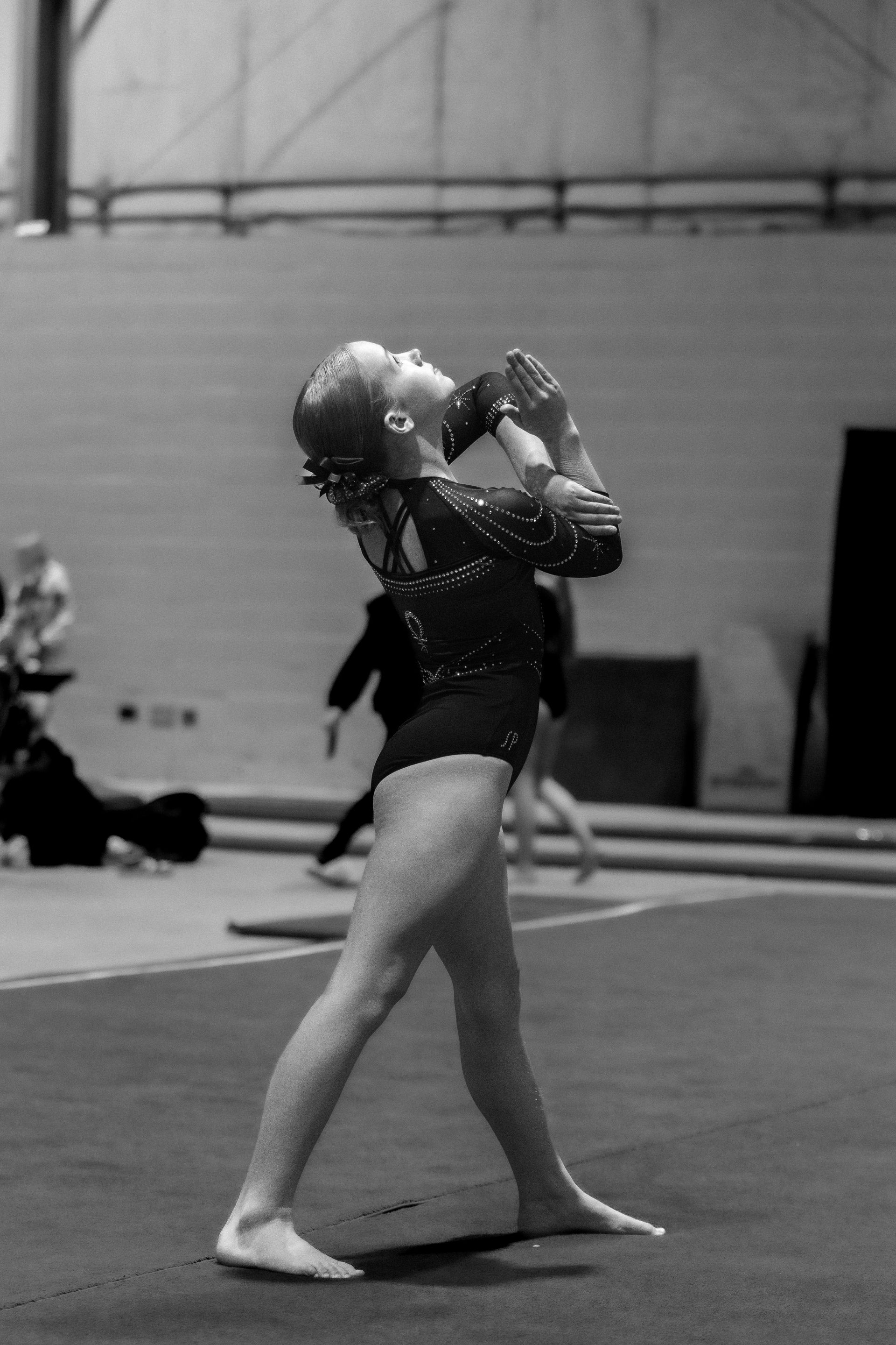 A black and white photo of a female gymnast on a balance beam.