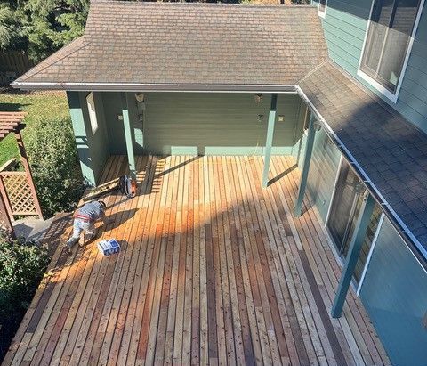 A wooden deck with a railing and a house in the background A wooden deck with a railing and a house in the background