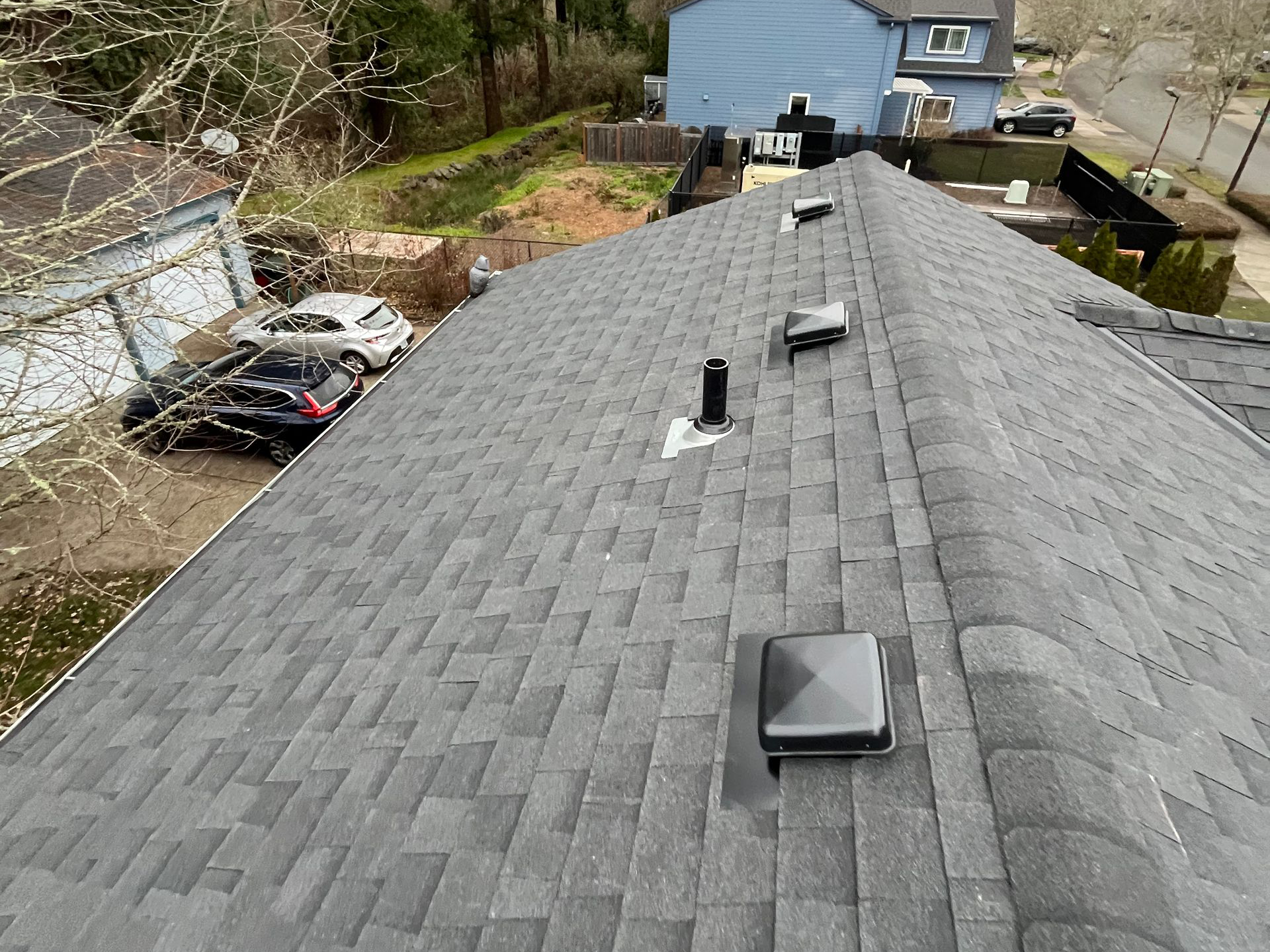 The roof of a house with a lot of trees in the background.