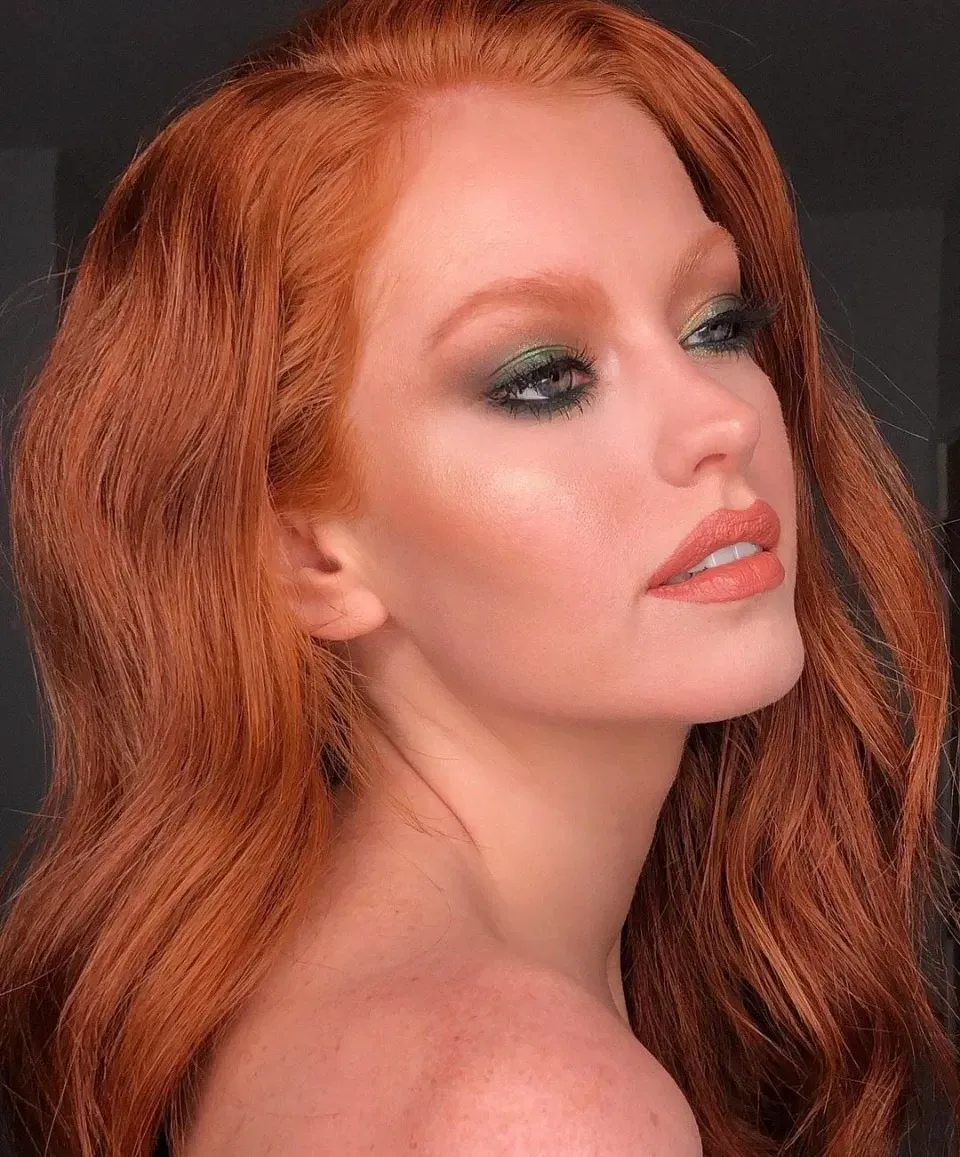 Eine Nahaufnahme des Gesichts einer Frau mit roten Haaren und grünem Augen-Makeup.