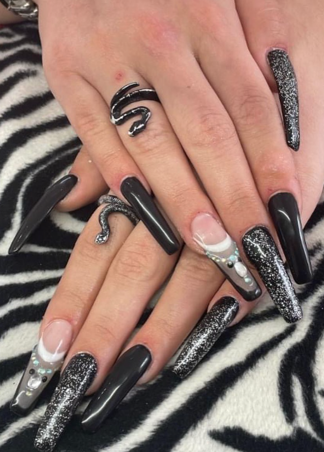 La mano di una donna con lunghe unghie nere e un anello di serpente