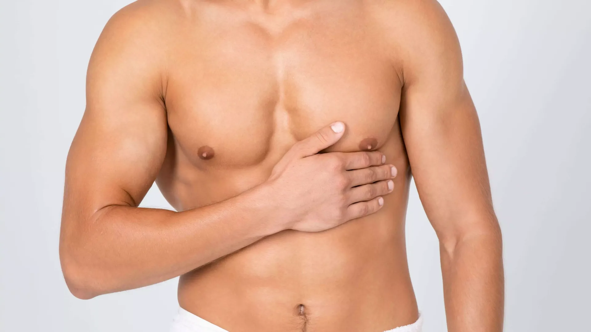 Un uomo a torso nudo si tiene il petto con la mano.