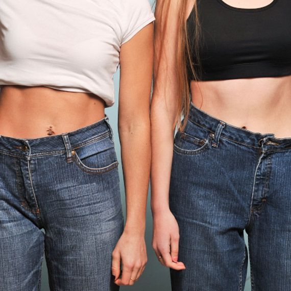 Two women standing next to each other wearing jeans and crop tops