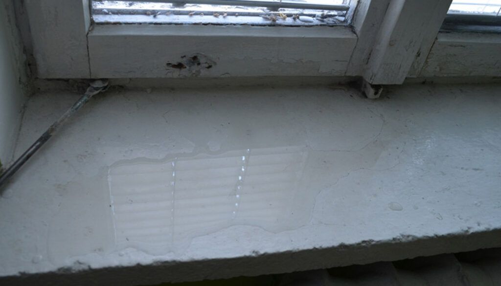 White windowsill under a window with a faint reflection on the surface