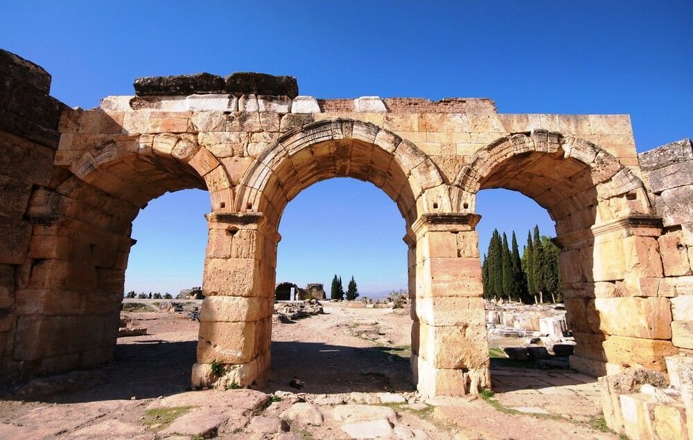Stone arches of an ancient structure against a blue sky, ruins of Hierapolis, Turkey.