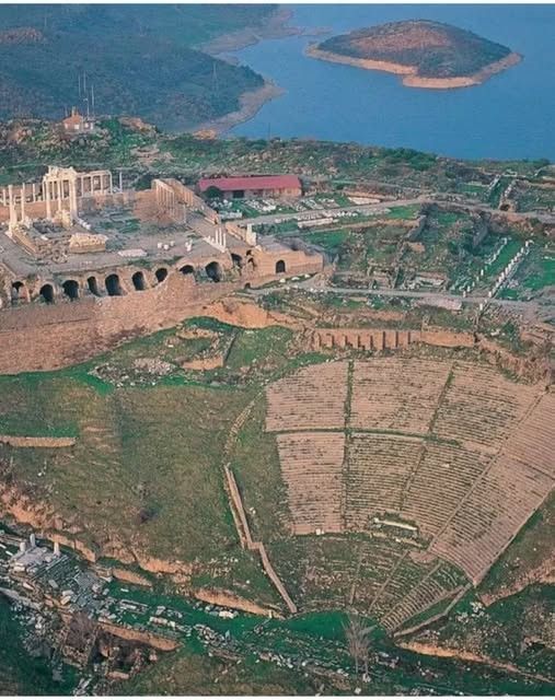 Aerial view of ancient ruins and a large amphitheater by a lake.