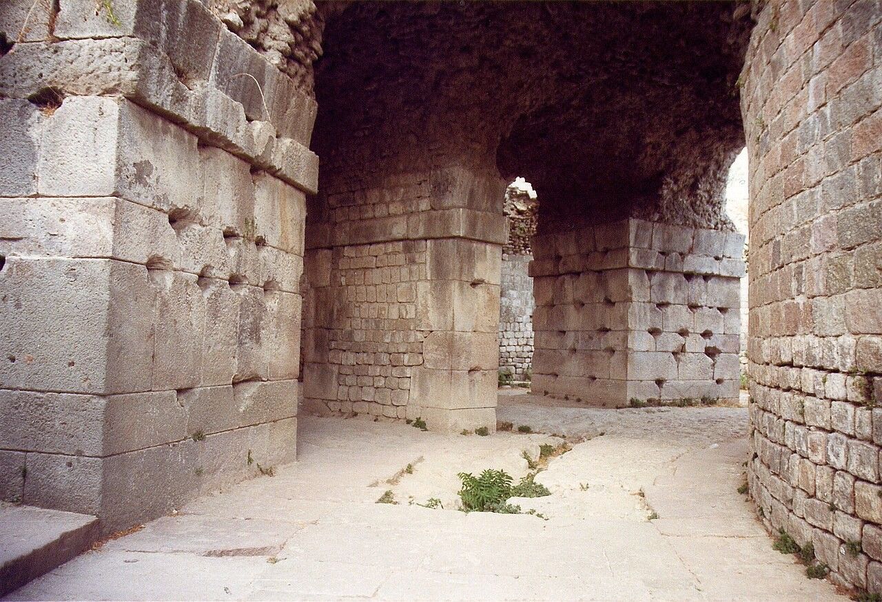 Interior view of ancient stone ruins with arched ceilings and supporting pillars.