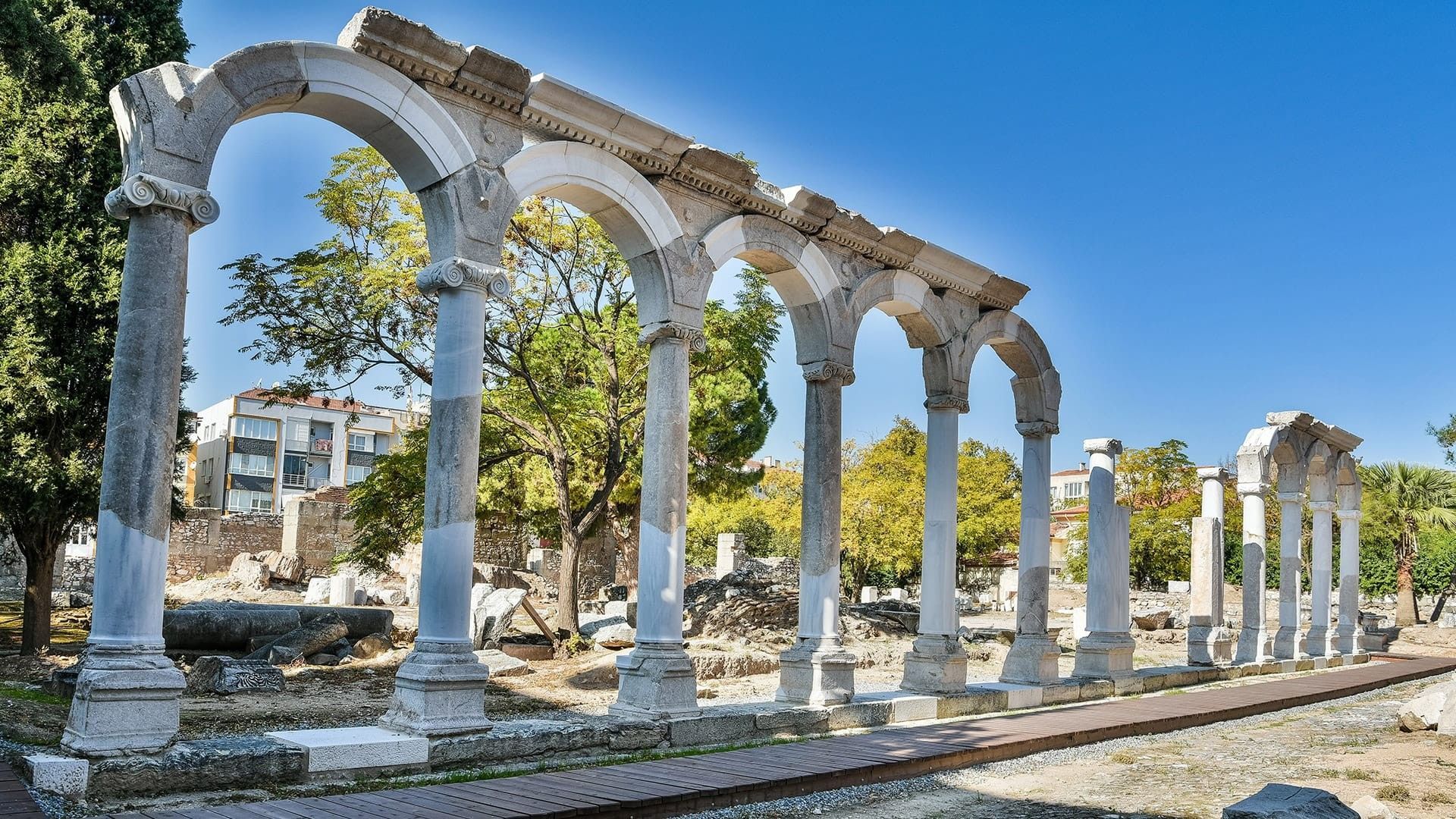 Row of ancient, white marble arches and columns, Izmir, Turkey, against a blue sky.