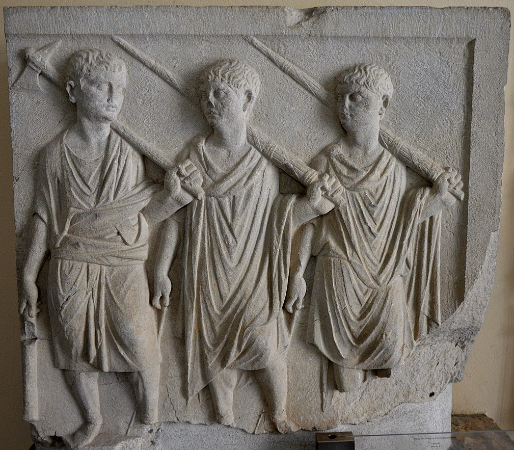 Stone relief sculpture of three figures in draped garments, possibly Roman.
