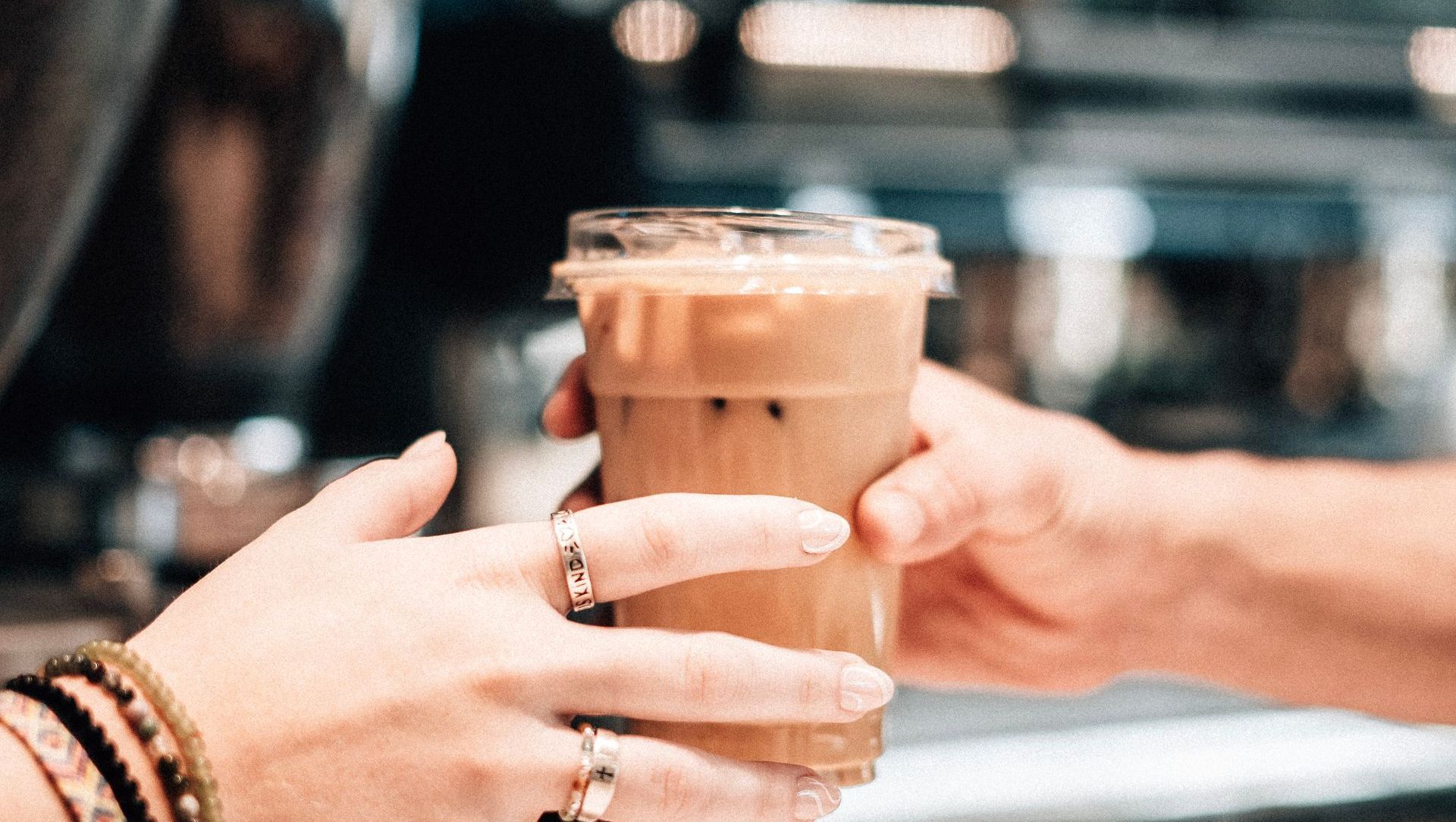 A person is holding a cup of iced coffee in their hand.
