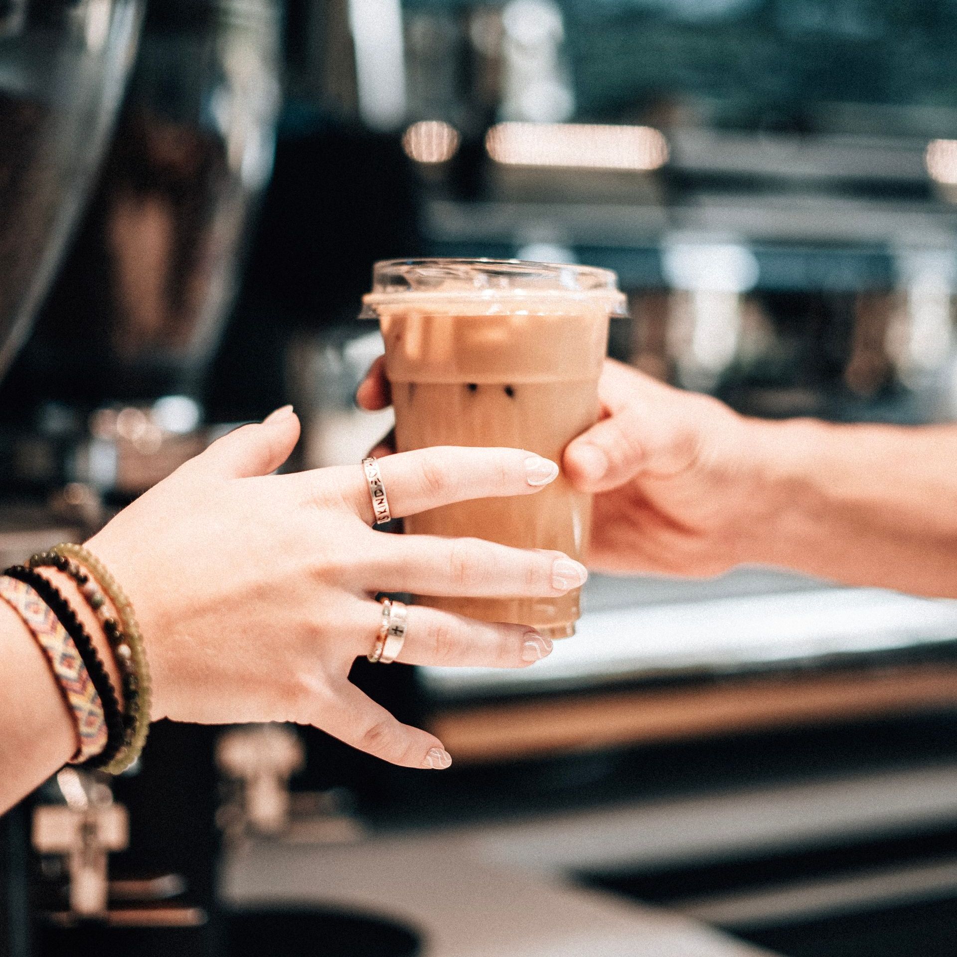 A barista is passing an iced coffee to a custome