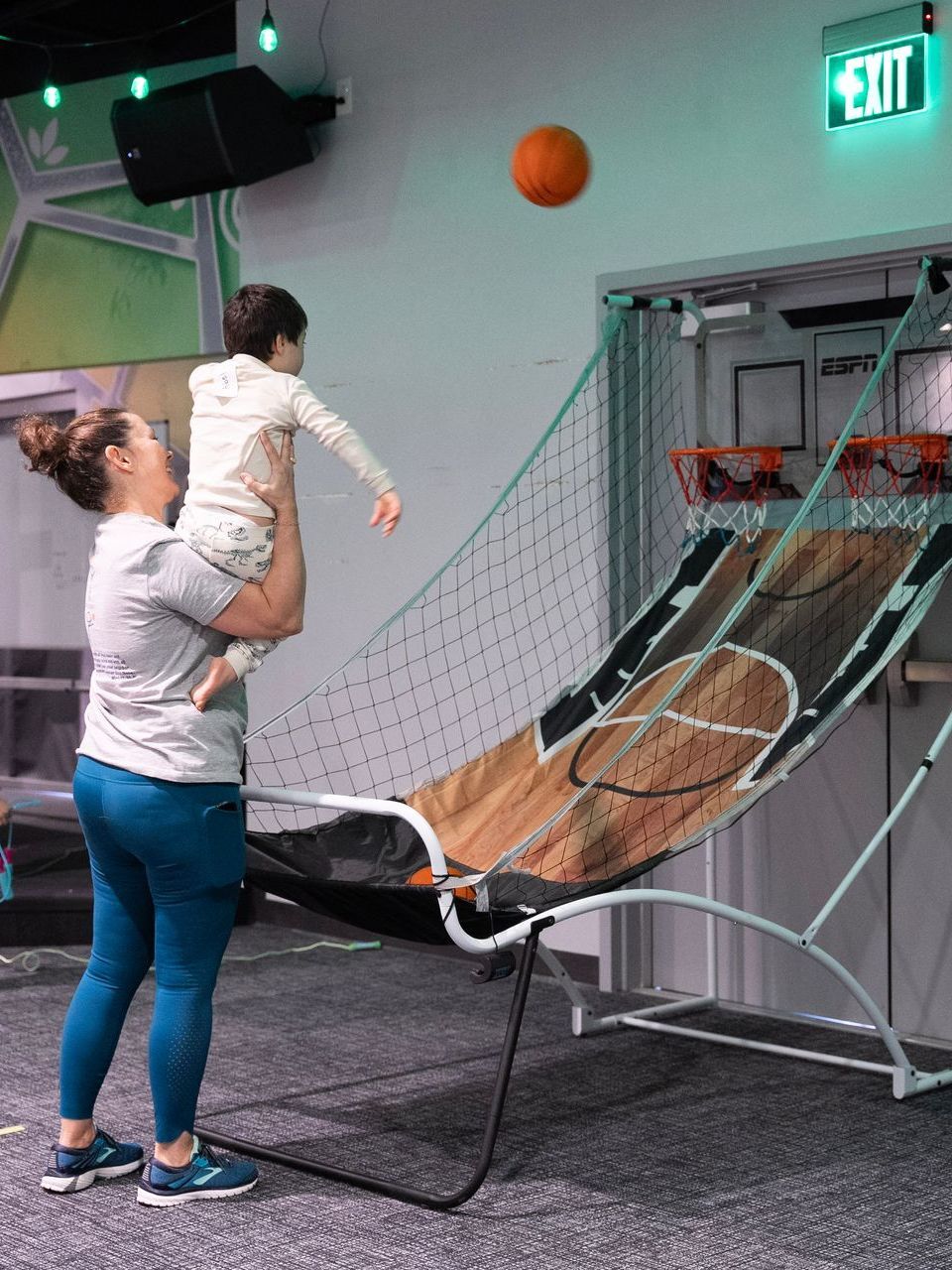A woman is holding a child in her arms while playing a game of basketball.