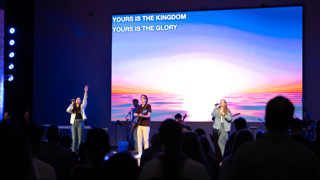A man is playing a guitar in front of a crowd of people in a church.