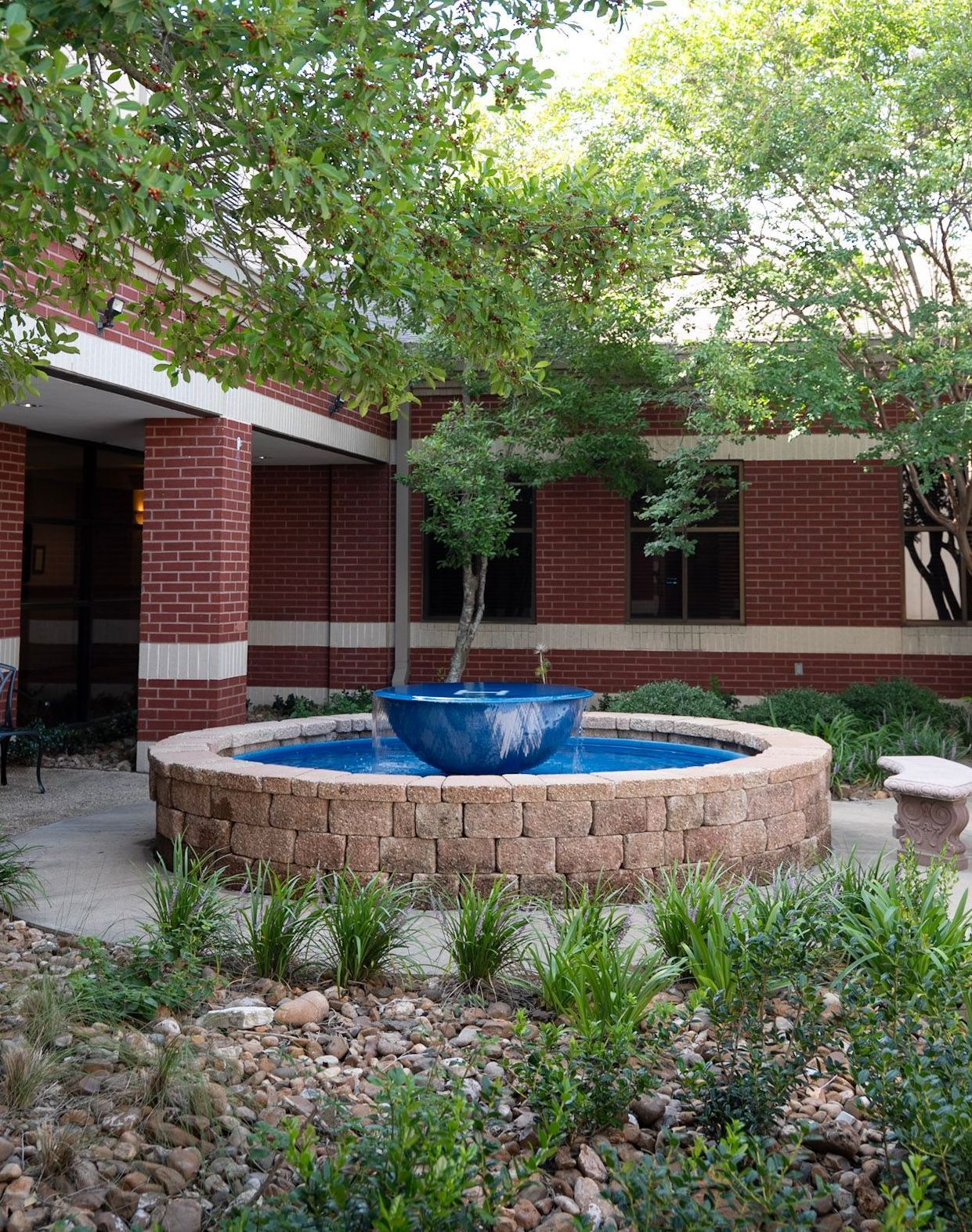 A brick building courtyard with a water fountain and small trees. at Christ Church columbarium