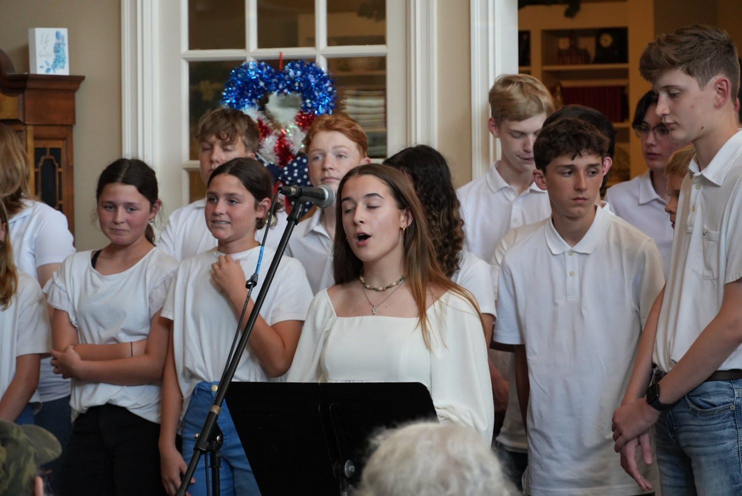 A group of young people are singing in front of a microphone.