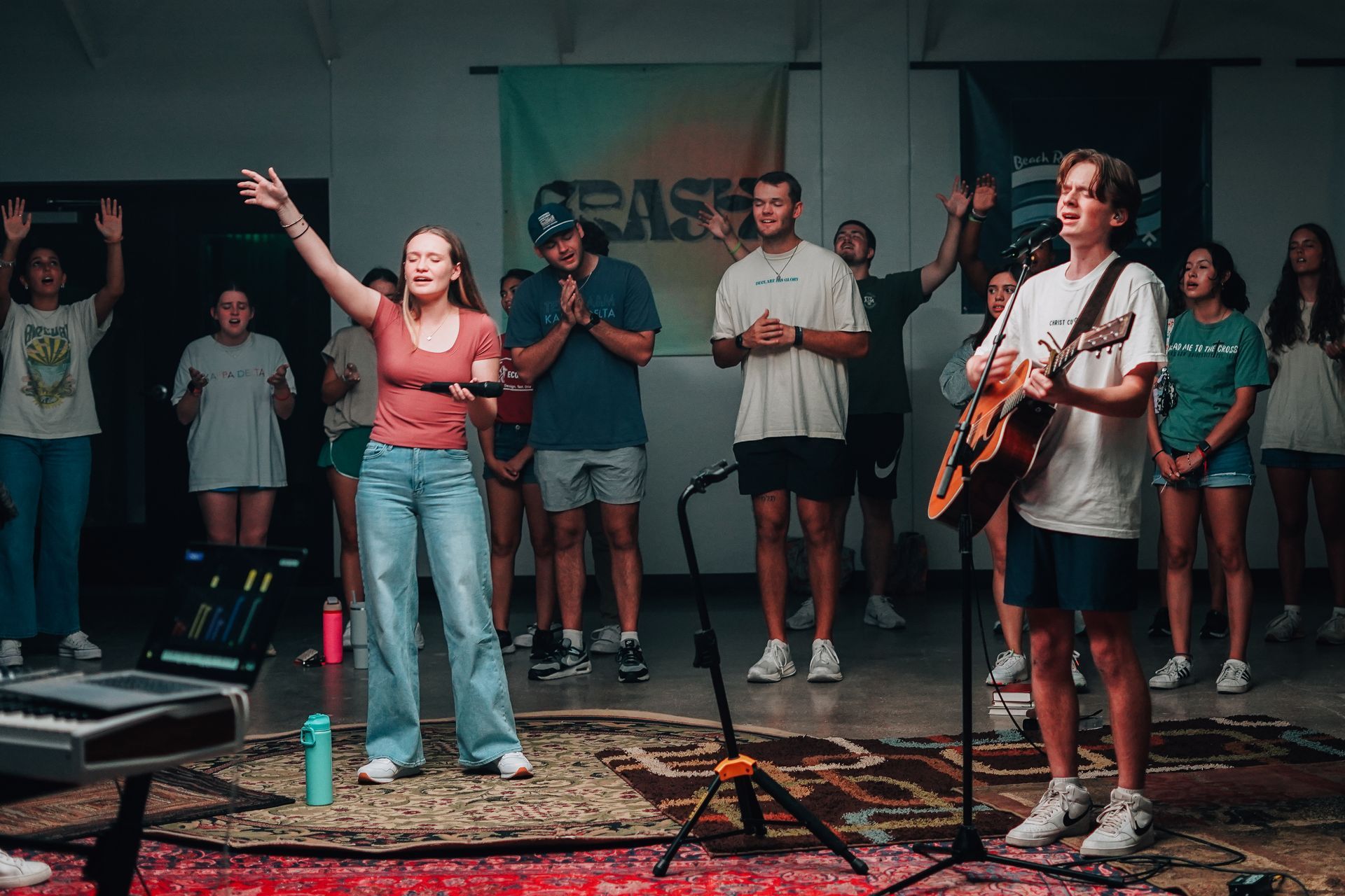 A group of young people are singing and worshipping together