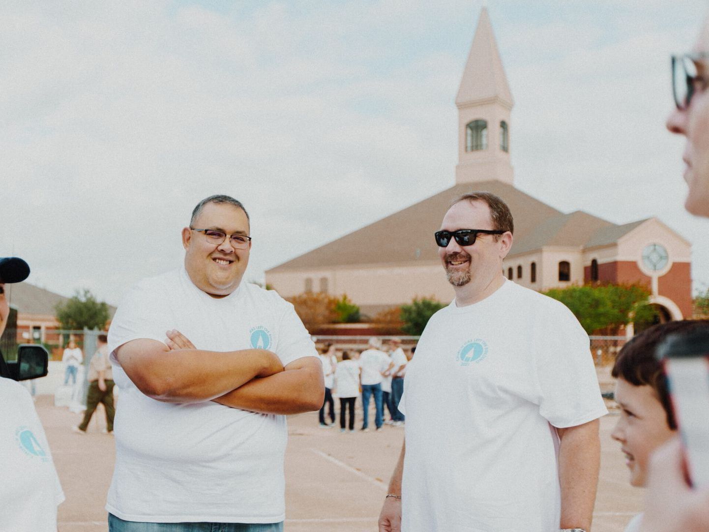 A group of men in white shirts are standing in front of a church.