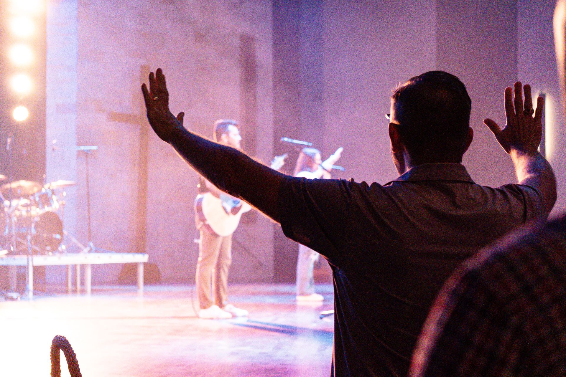 A man is standing on a stage with his hands in the air.