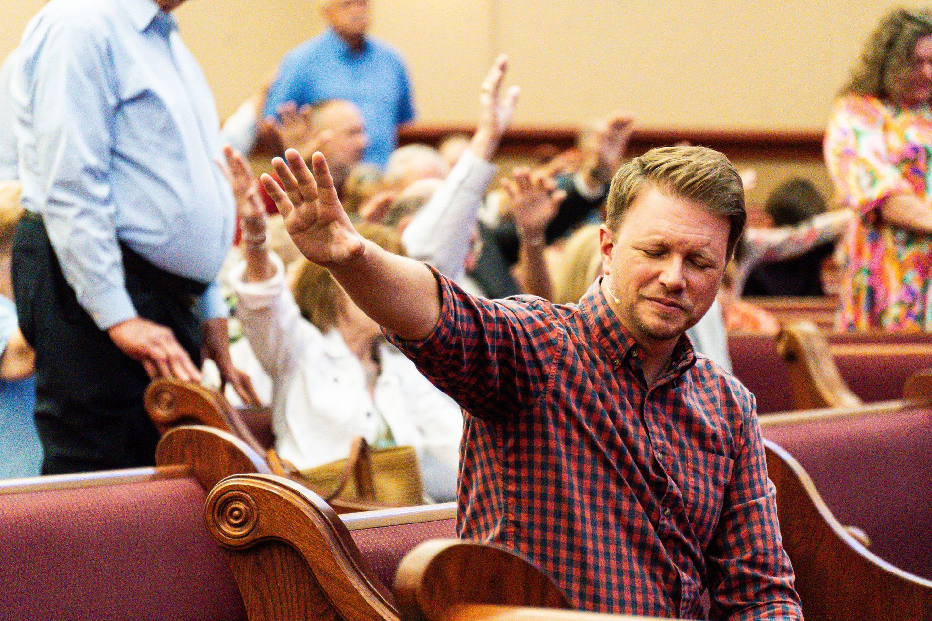 A man is sitting in a church with his hands in the air.