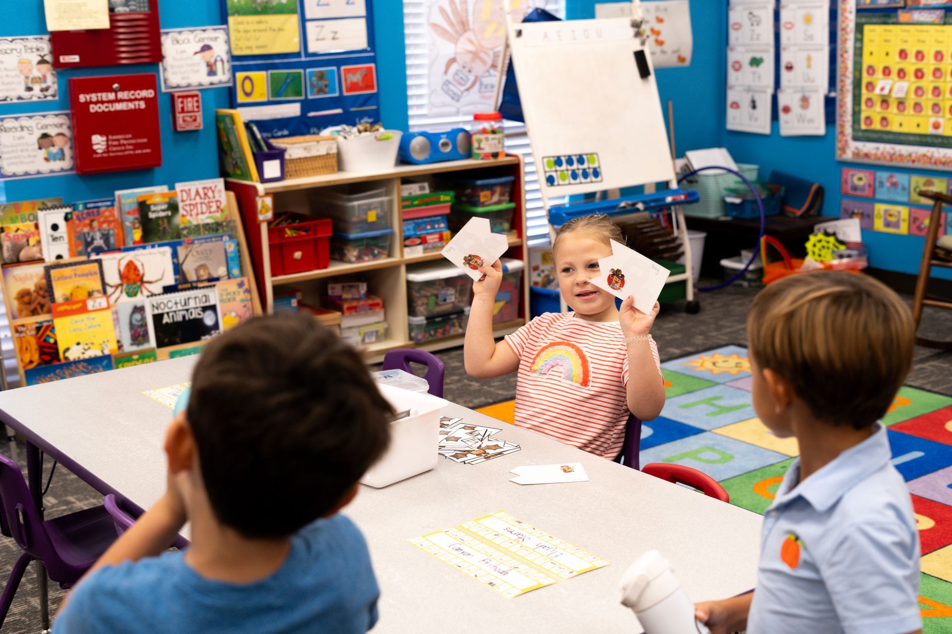 A group of children are sitting at a table in a classroom.