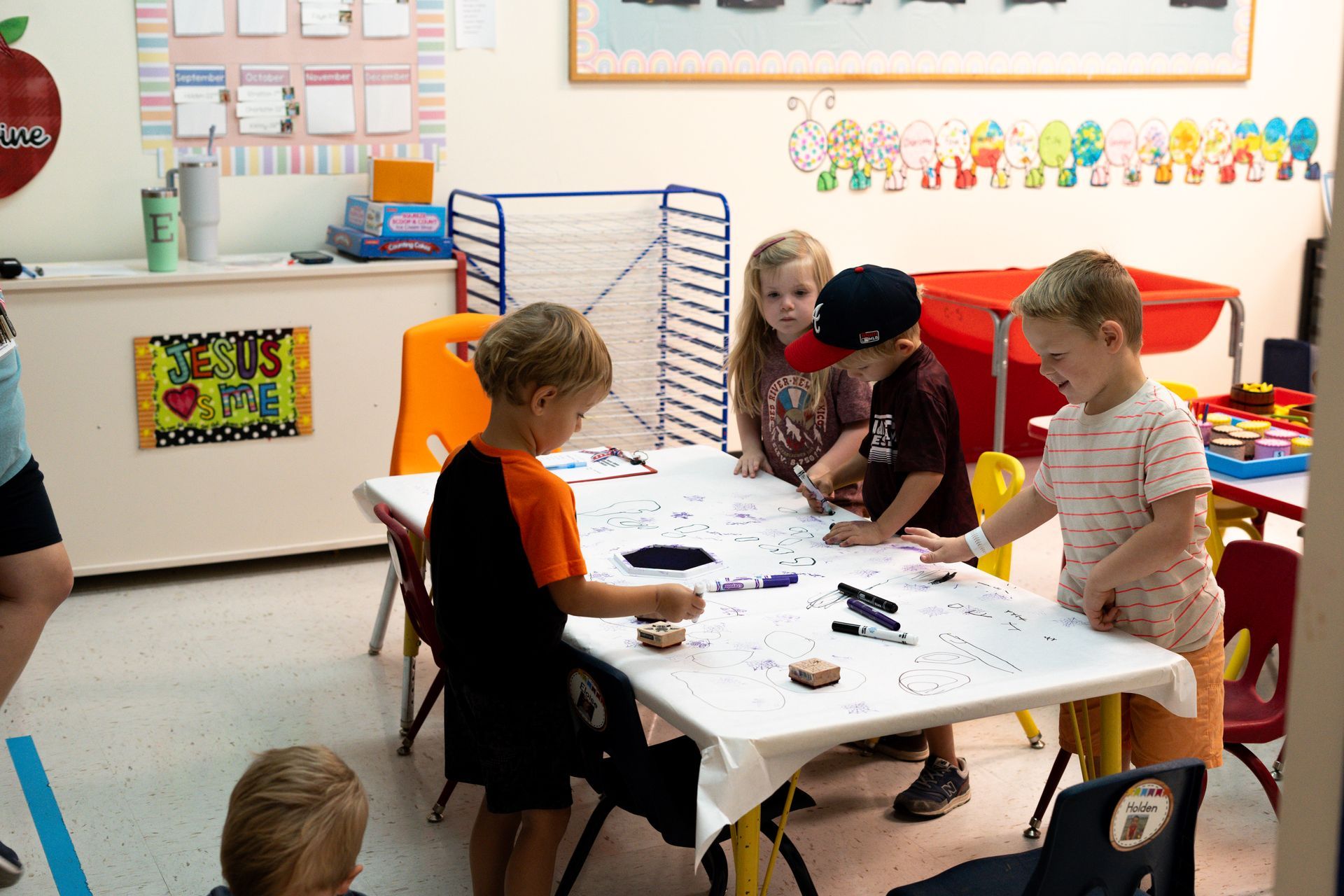 A group of children are sitting at a table in a classroom.