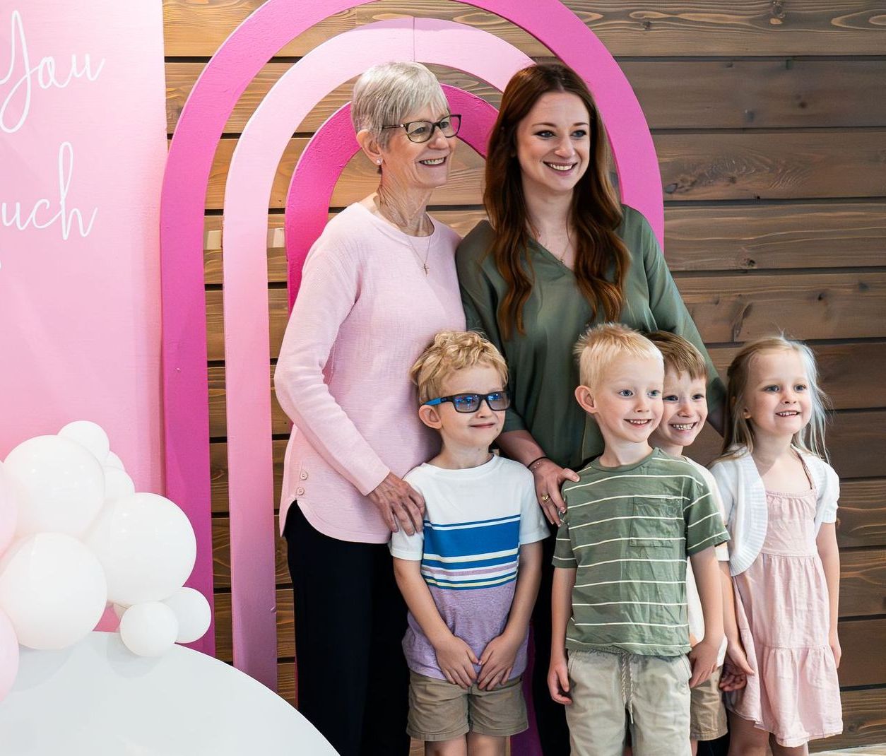 A group of people are posing for a picture in front of a pink rainbow.