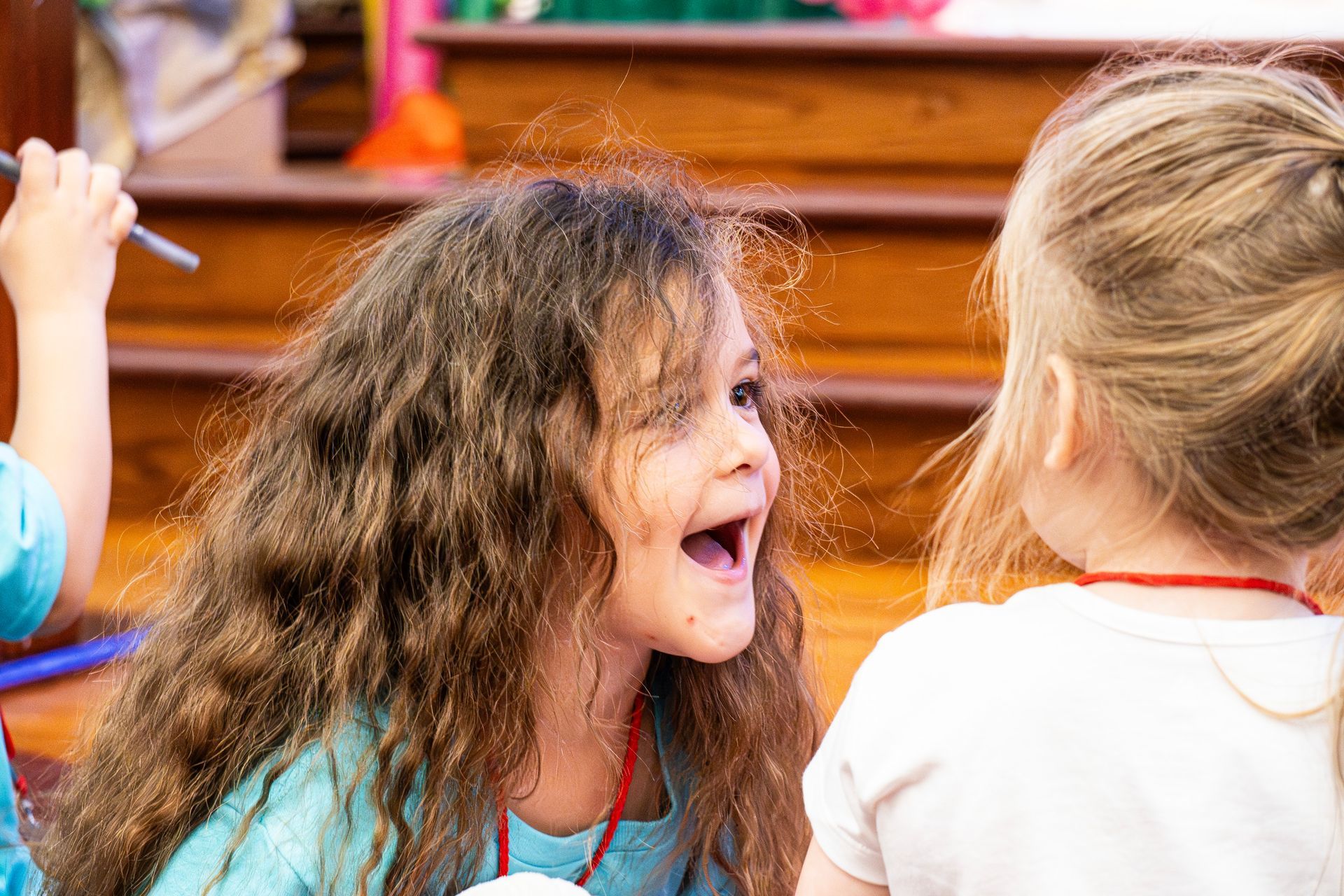 Two little girls are sitting on the floor talking to each other.