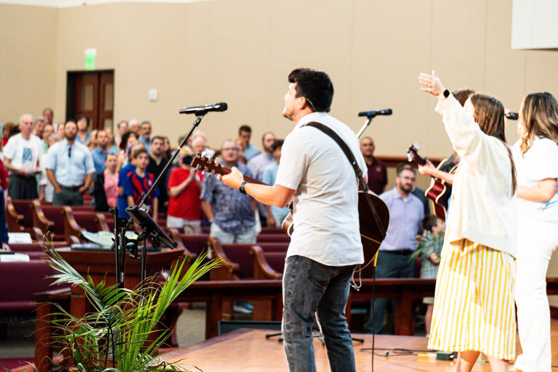 A man is playing a guitar in front of a crowd of people in a church.