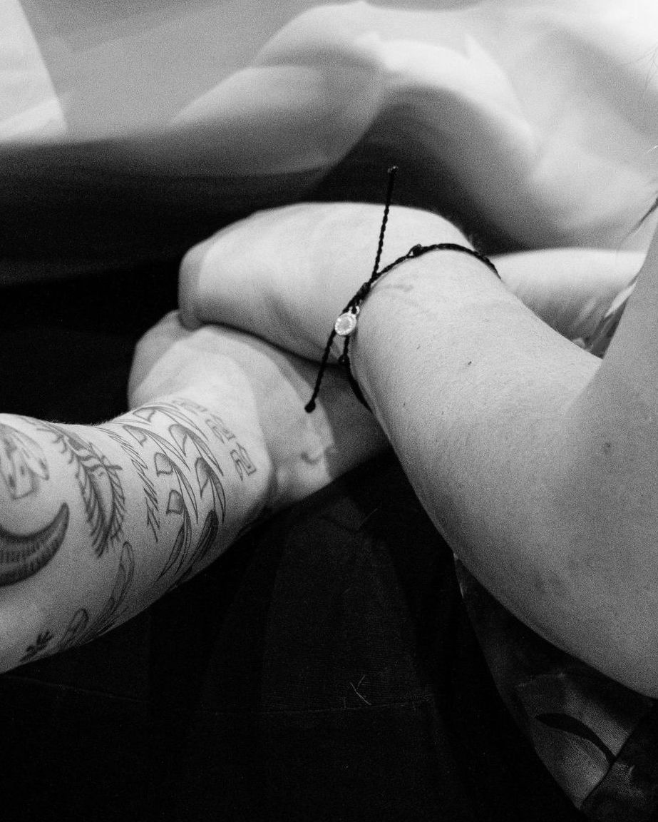A person with a tattoo on their arm is holding another person 's hand