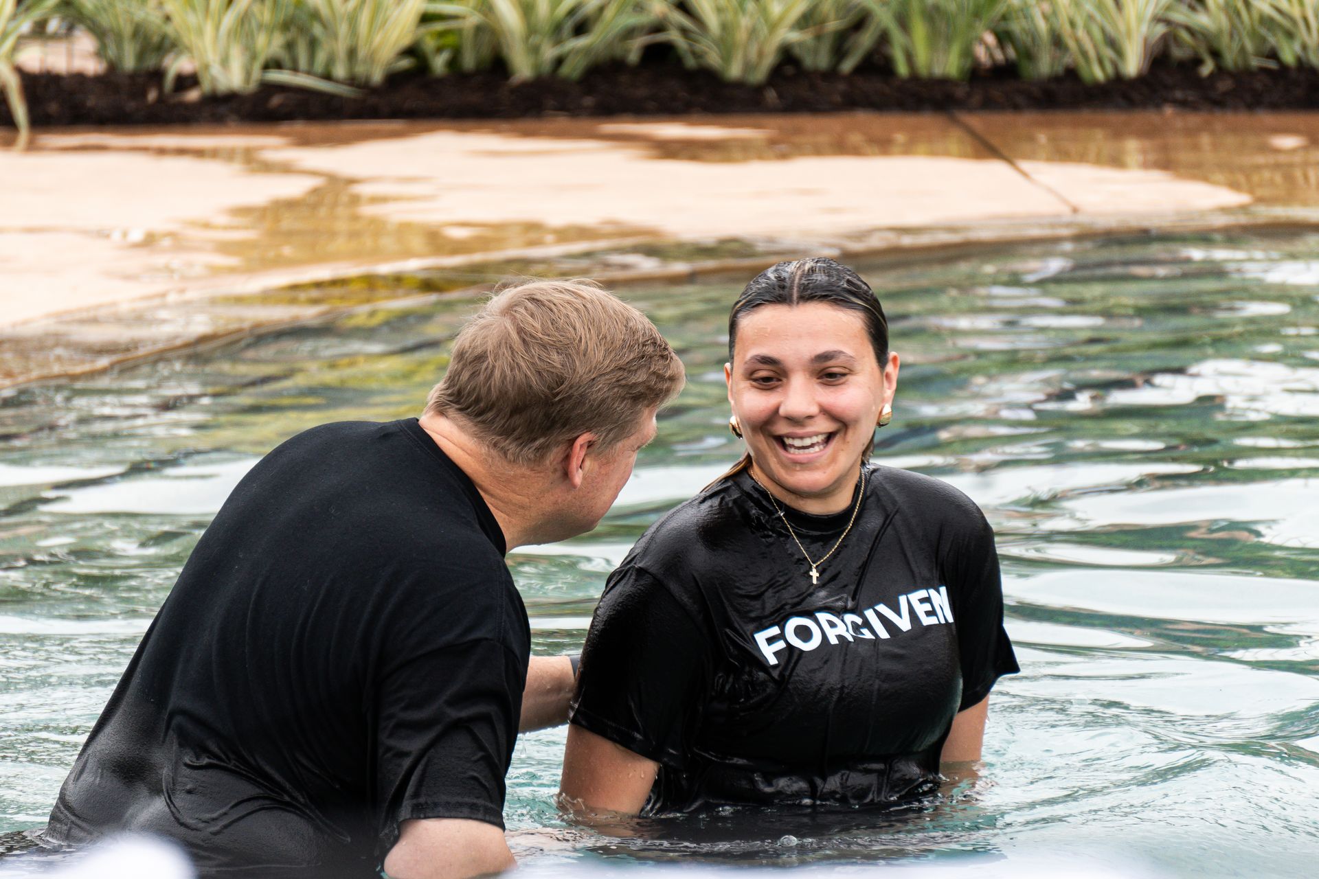 A pastor is baptizing a woman in a pool.