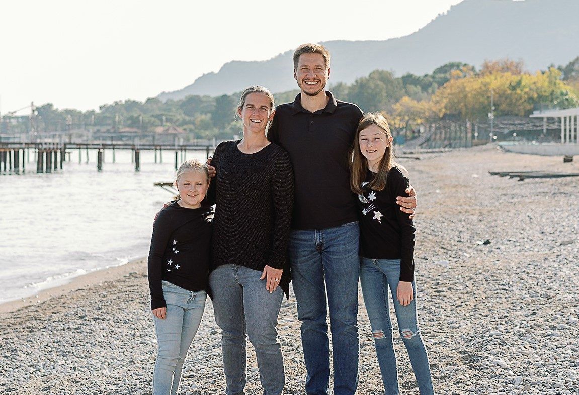 A family is posing for a picture on the beach.