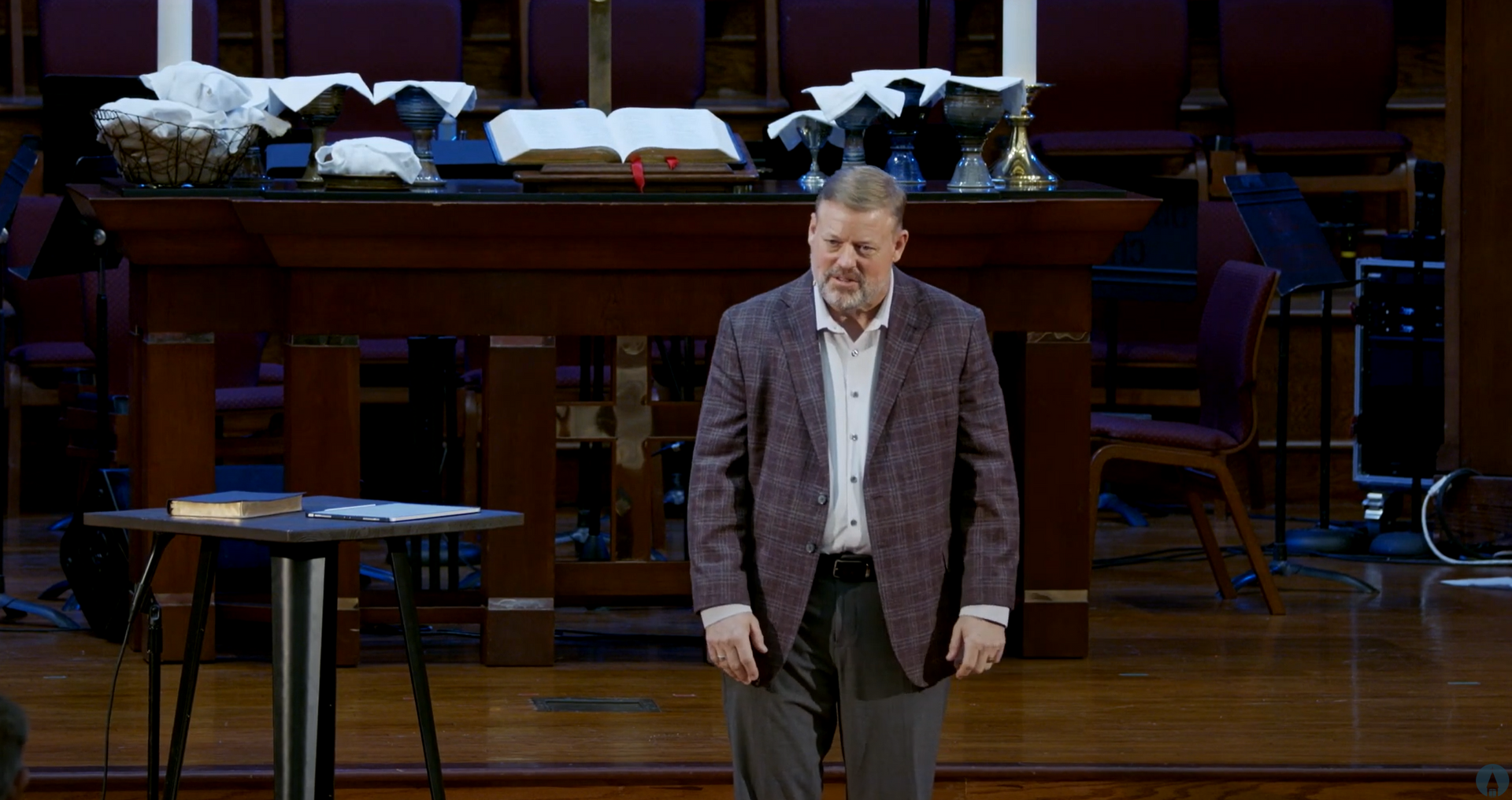 Man in blazer stands at a podium in a church sanctuary, smiling slightly. Christ Church in College Station TX