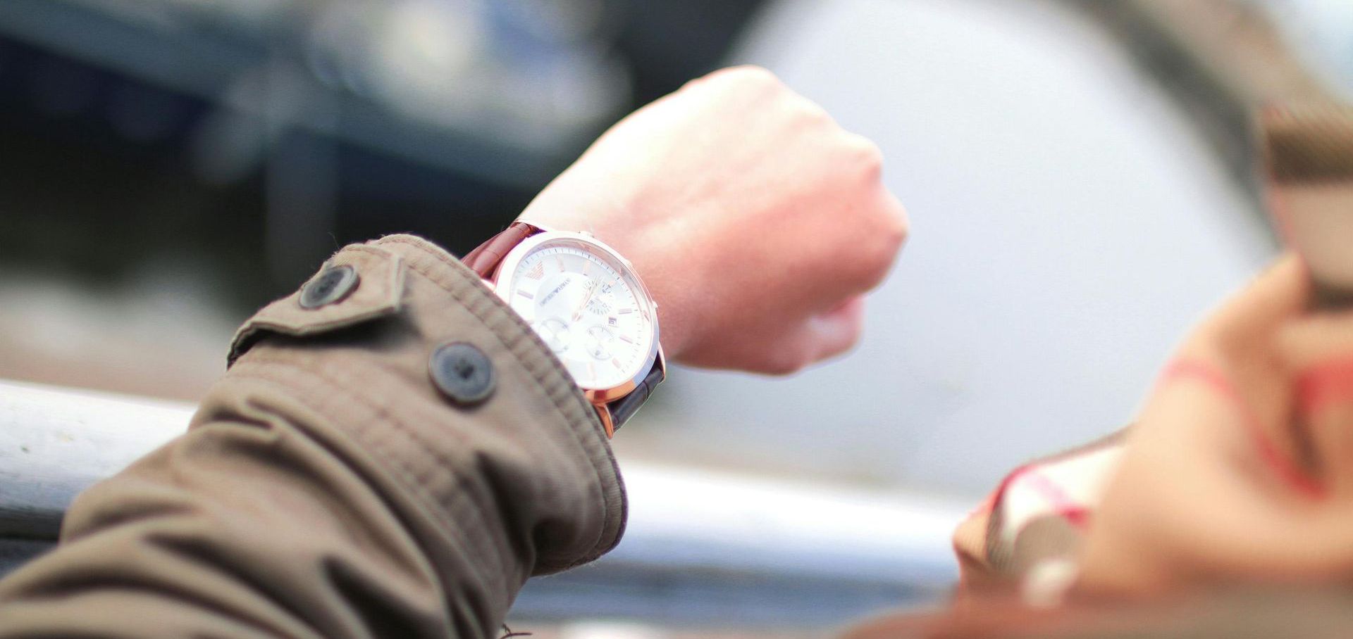 A person wearing a brown jacket looks at their wristwatch. Christ Church in College Station TX