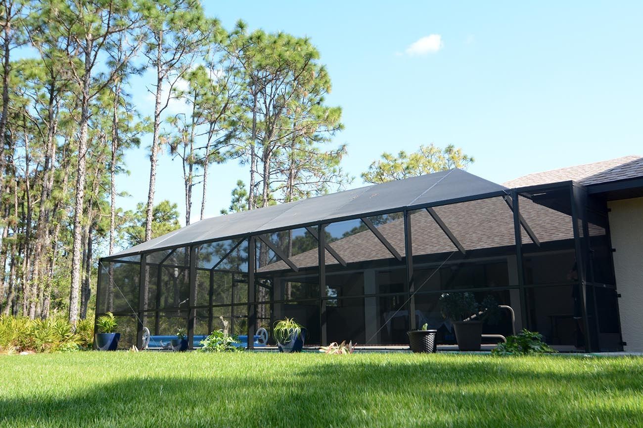 Screened porch on a modern house beside a grassy yard and tall pine trees