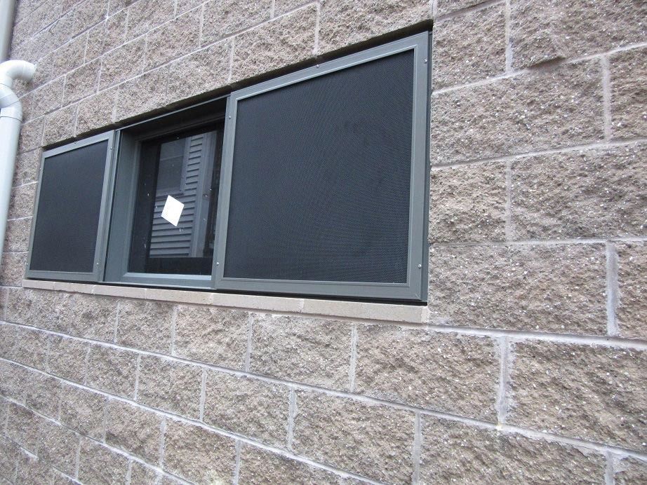 Two dark-framed windows set in a tan brick wall, one slightly open with a white note inside.