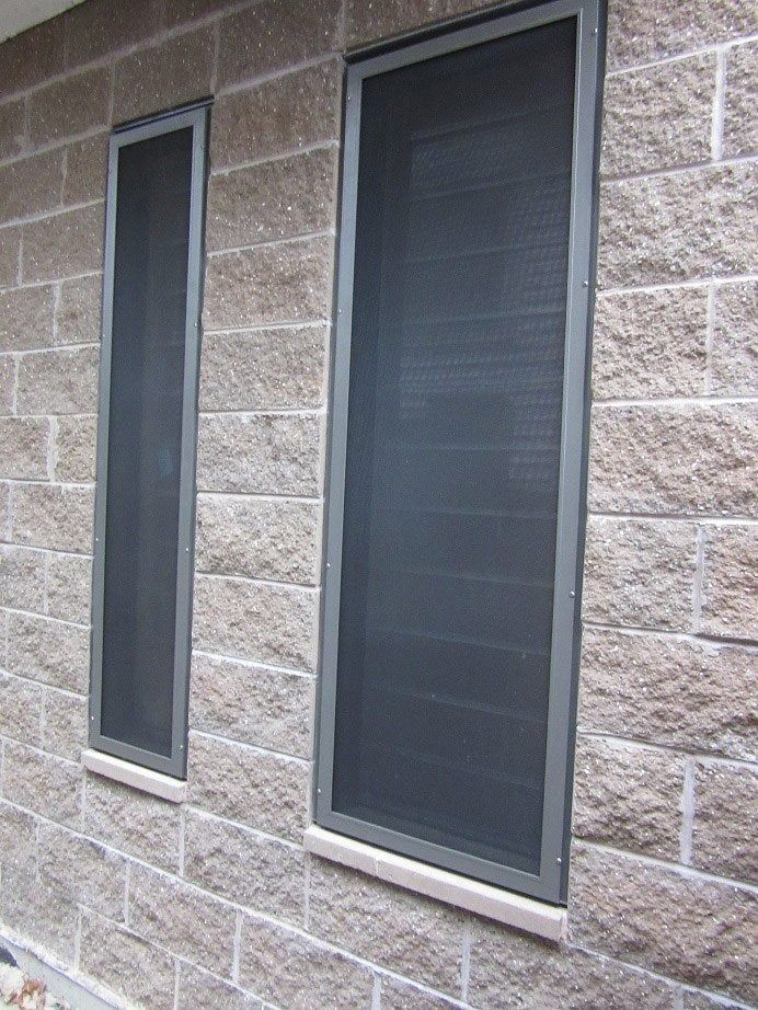 Two dark-tinted windows set in a tan stone wall