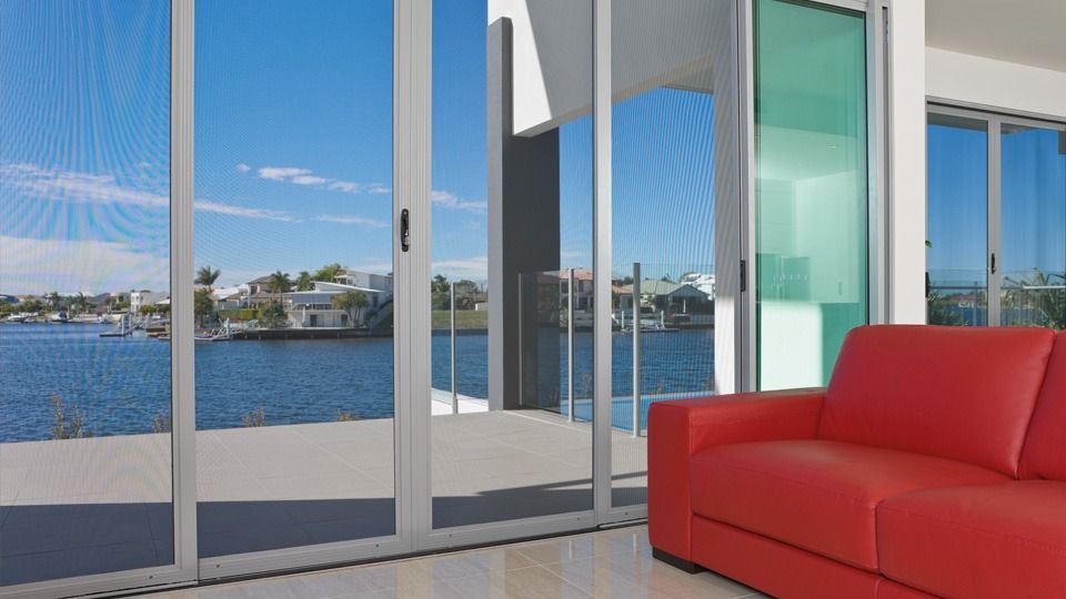 Sliding glass balcony doors overlooking a bright waterfront view with curtains inside