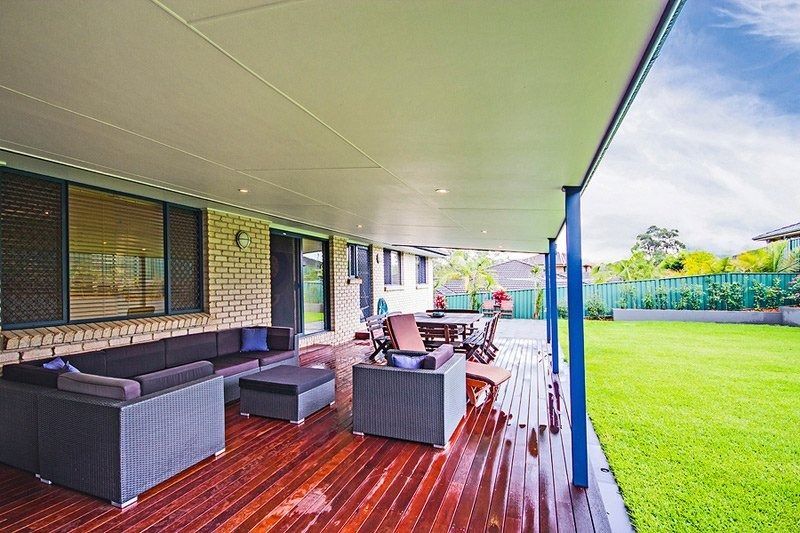 Covered patio with gray outdoor seating on a wooden deck beside a green lawn
