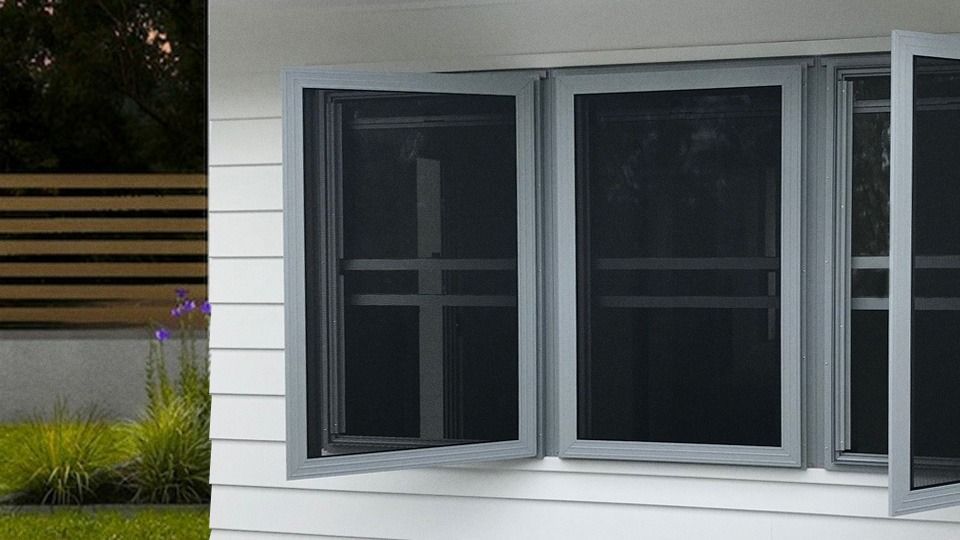 Interior view through frosted sliding windows overlooking a sunny green yard and trees.