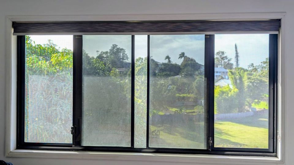 Interior view of a four-panel window with frosted glass and a sunny green landscape outside