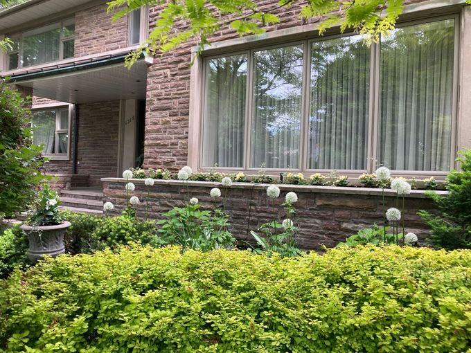 Une grande maison en briques avec beaucoup de fenêtres et de fleurs devant.