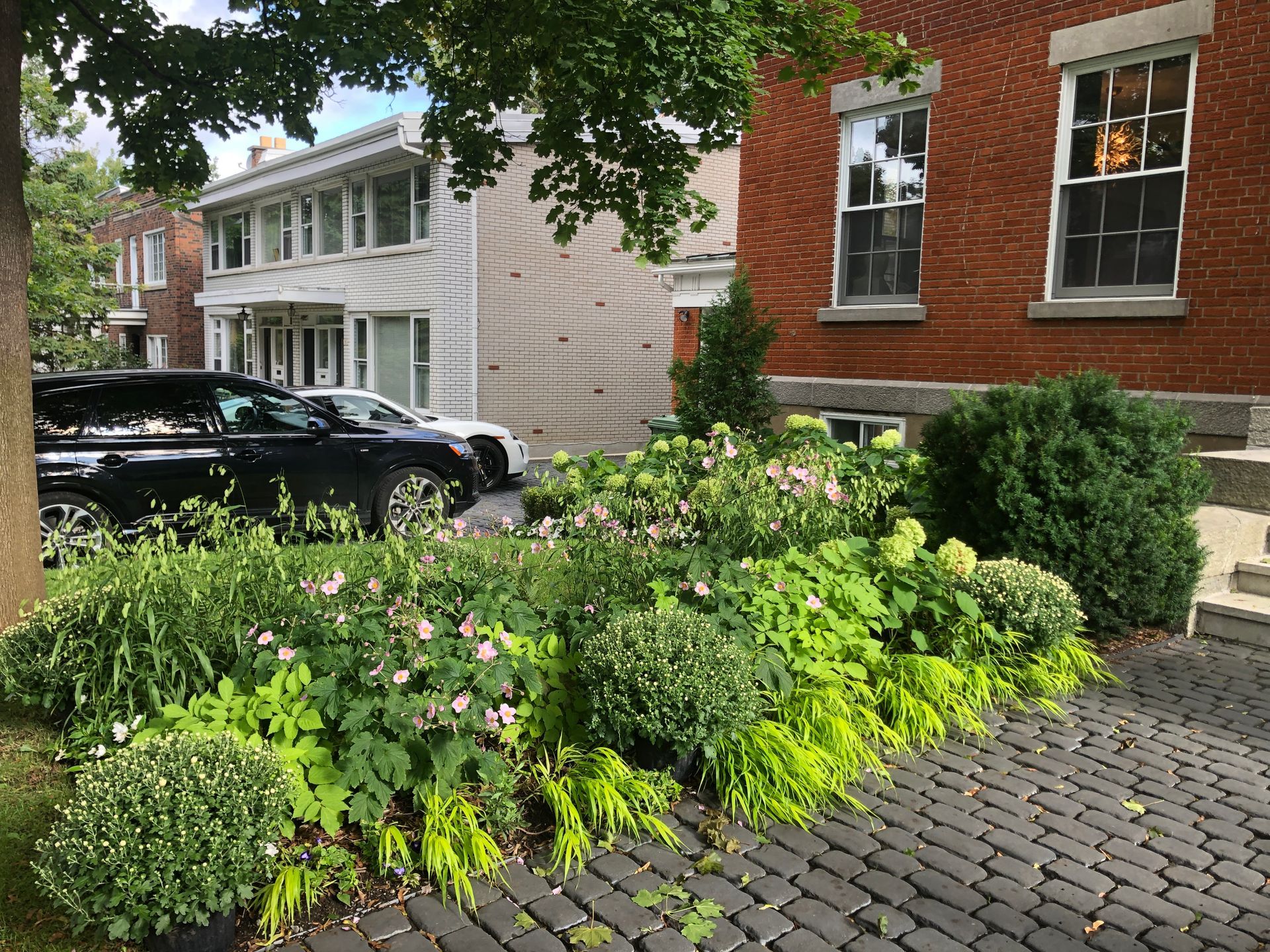 Une voiture noire est garée devant un bâtiment en briques.