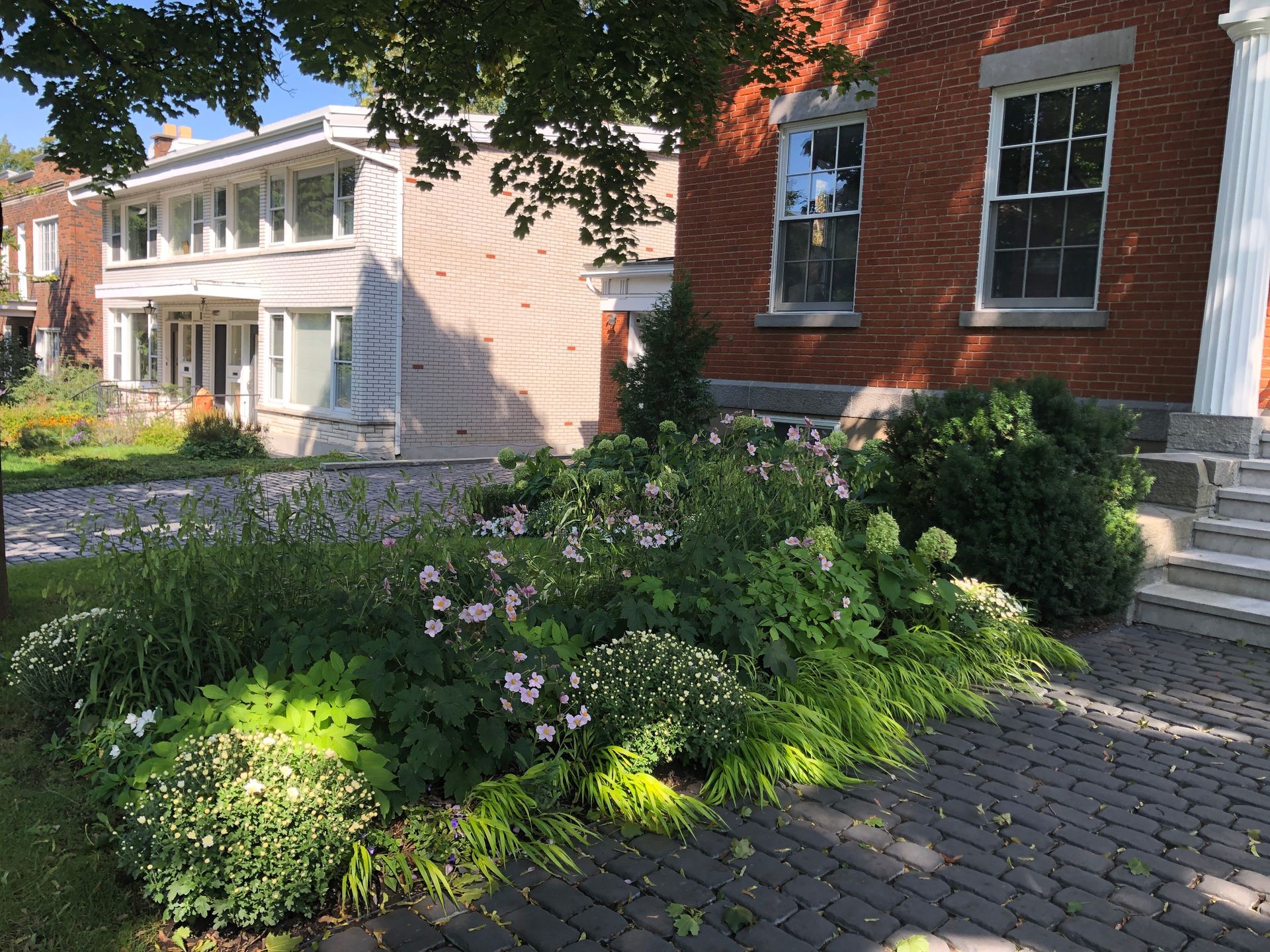 Une maison en brique avec un jardin verdoyant devant elle
