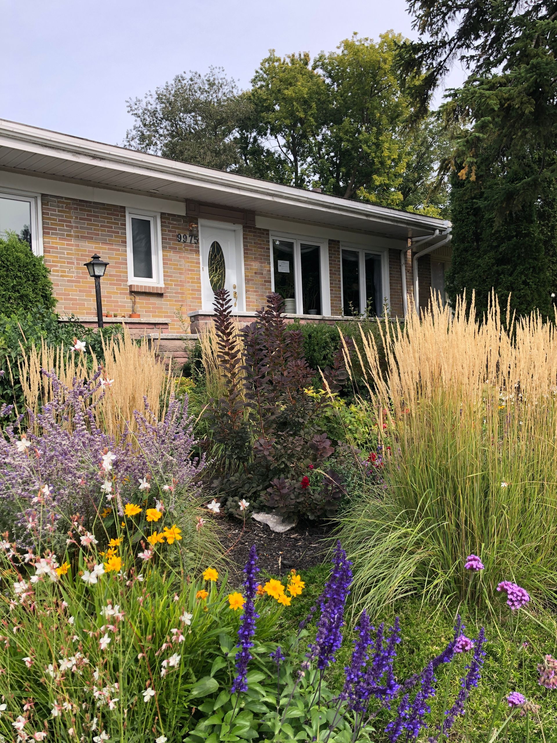 Une maison en briques avec un jardin verdoyant devant elle.