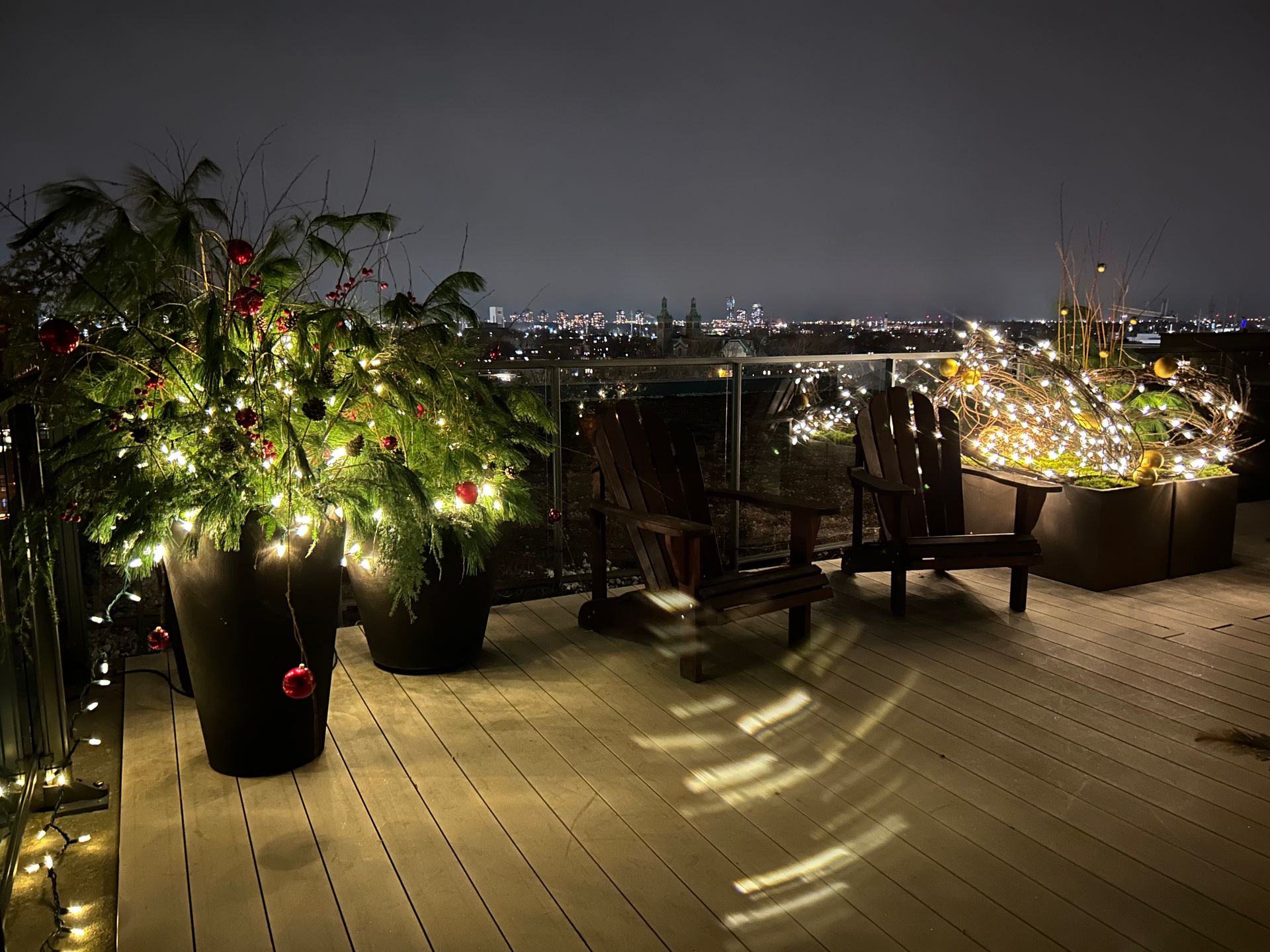 Un balcon décoré pour Noël avec vue sur la ville la nuit.
