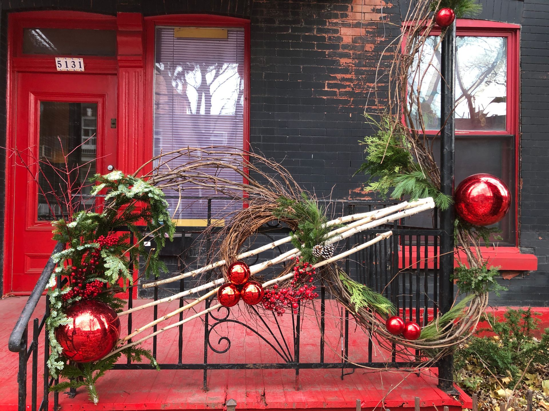 Un banc rouge est décoré de décorations de Noël devant une porte rouge.